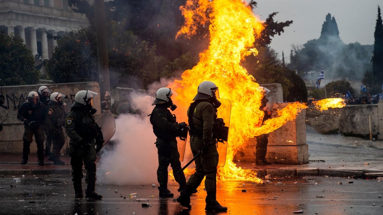 Griechische Bereitschaftspolizisten stehen vor einer Feuerwand, verursacht durch einen Molotow-Cocktail. Griechische Bereitschaftspolizisten stehen vor einer Feuerwand, verursacht durch einen Molotow-Cocktail.