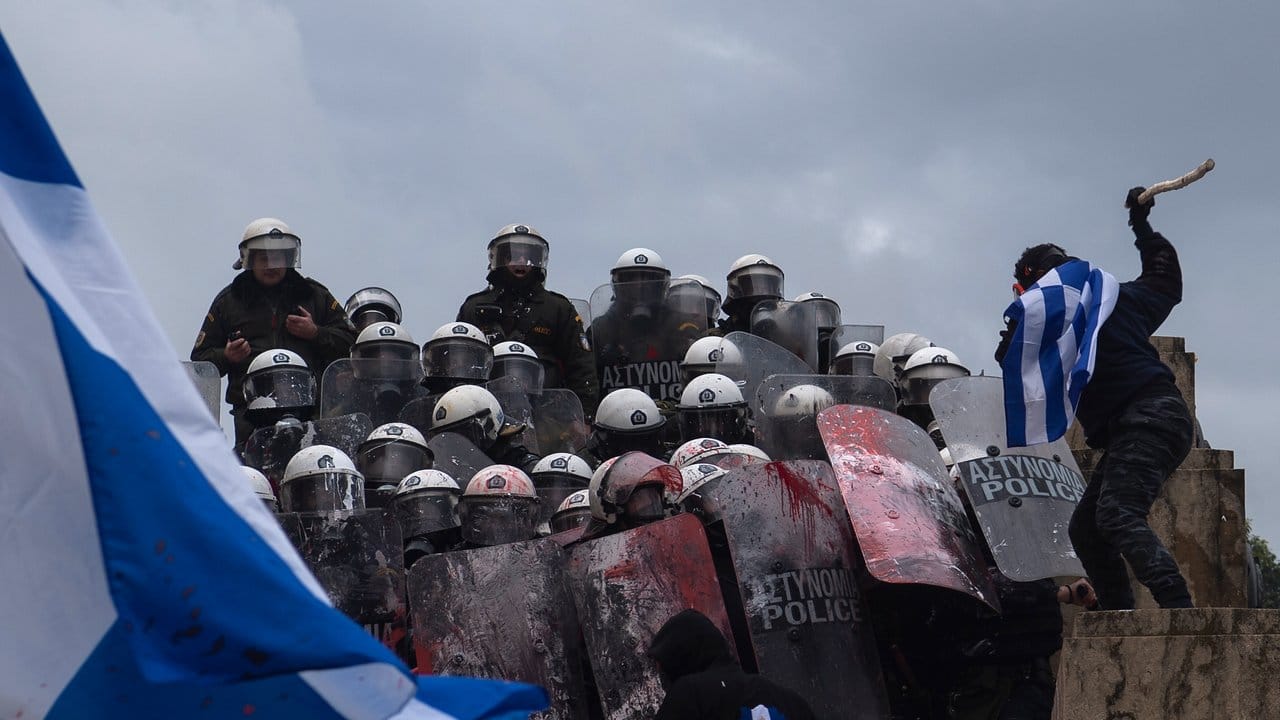 Ein Teilnehmer einer Demonstration gegen die geplante Namensänderung Mazedoniens in Nord-Mazedonien schlägt mit einem Stock auf Bereitschaftspolizisten ein. Ein Teilnehmer einer Demonstration gegen die geplante Namensänderung Mazedoniens in Nord-Mazedonien schlägt mit einem Stock auf Bereitschaftspolizisten ein.