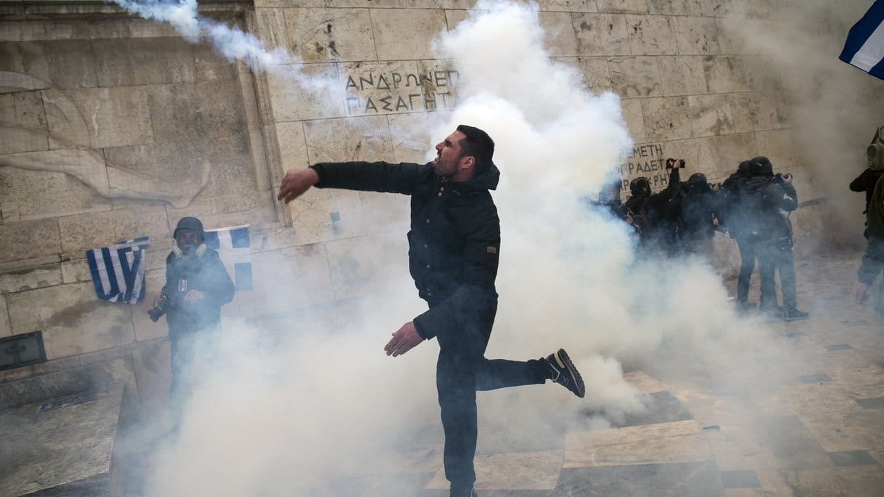 Straßenkampf in Athen: Ein Demonstrant wirft eine Tränengasgranate auf Bereitschaftspolizisten nahe dem Parlamentsgebäude. Straßenkampf in Athen: Ein Demonstrant wirft eine Tränengasgranate auf Bereitschaftspolizisten nahe dem Parlamentsgebäude.