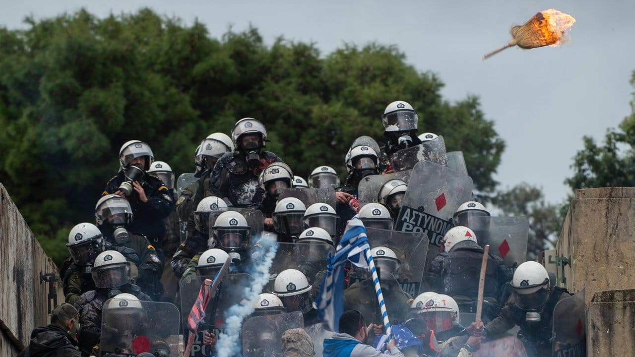 Ein brennender Strohbesen fliegt auf Bereitschaftspolizisten zu, die in Athen von Demonstranten attackiert werden. Ein brennender Strohbesen fliegt auf Bereitschaftspolizisten zu, die in Athen von Demonstranten attackiert werden.