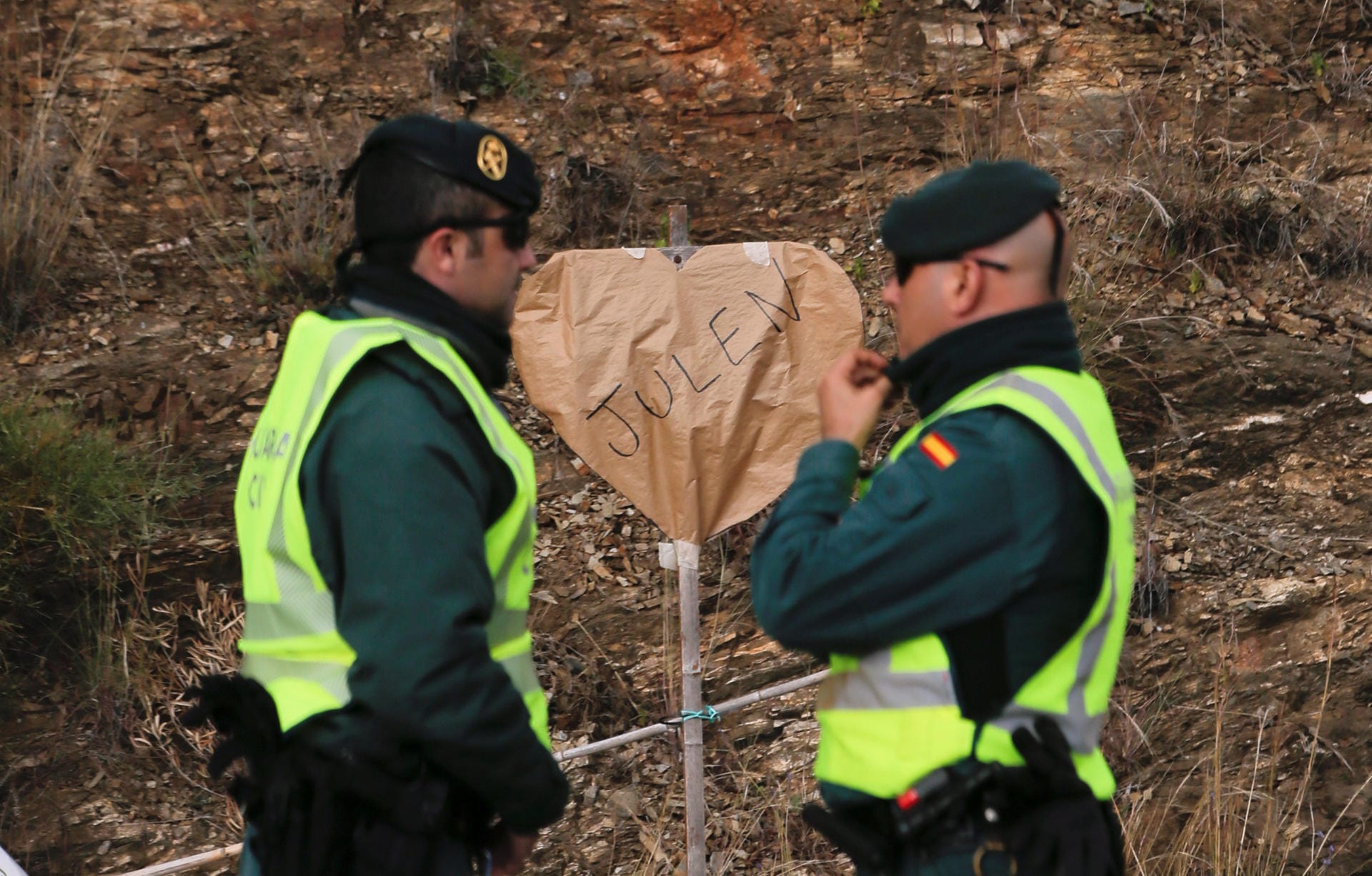 Spanische Polizisten stehen vor einem herzförmigen Schild, das Julens Namen trägt. Seit einer Woche unterstützen die Anwohner Julens Eltern nach Leibeskräften – mit Essen, Schlafplätzen und ermunternden Worten.