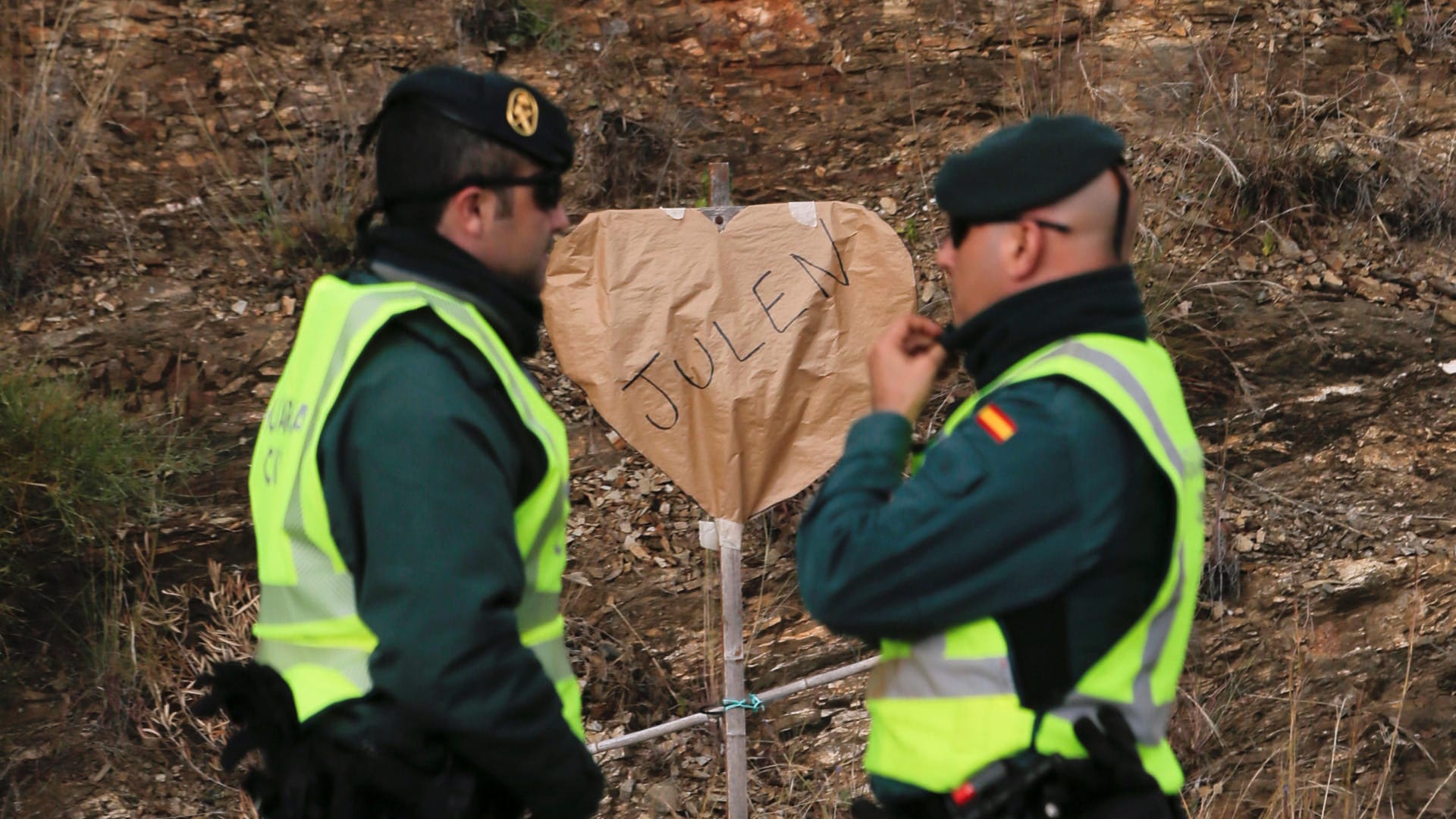 Spanische Polizisten stehen vor einem herzförmigen Schild, das Julens Namen trägt. Seit einer Woche unterstützen die Anwohner Julens Eltern nach Leibeskräften – mit Essen, Schlafplätzen und ermunternden Worten.