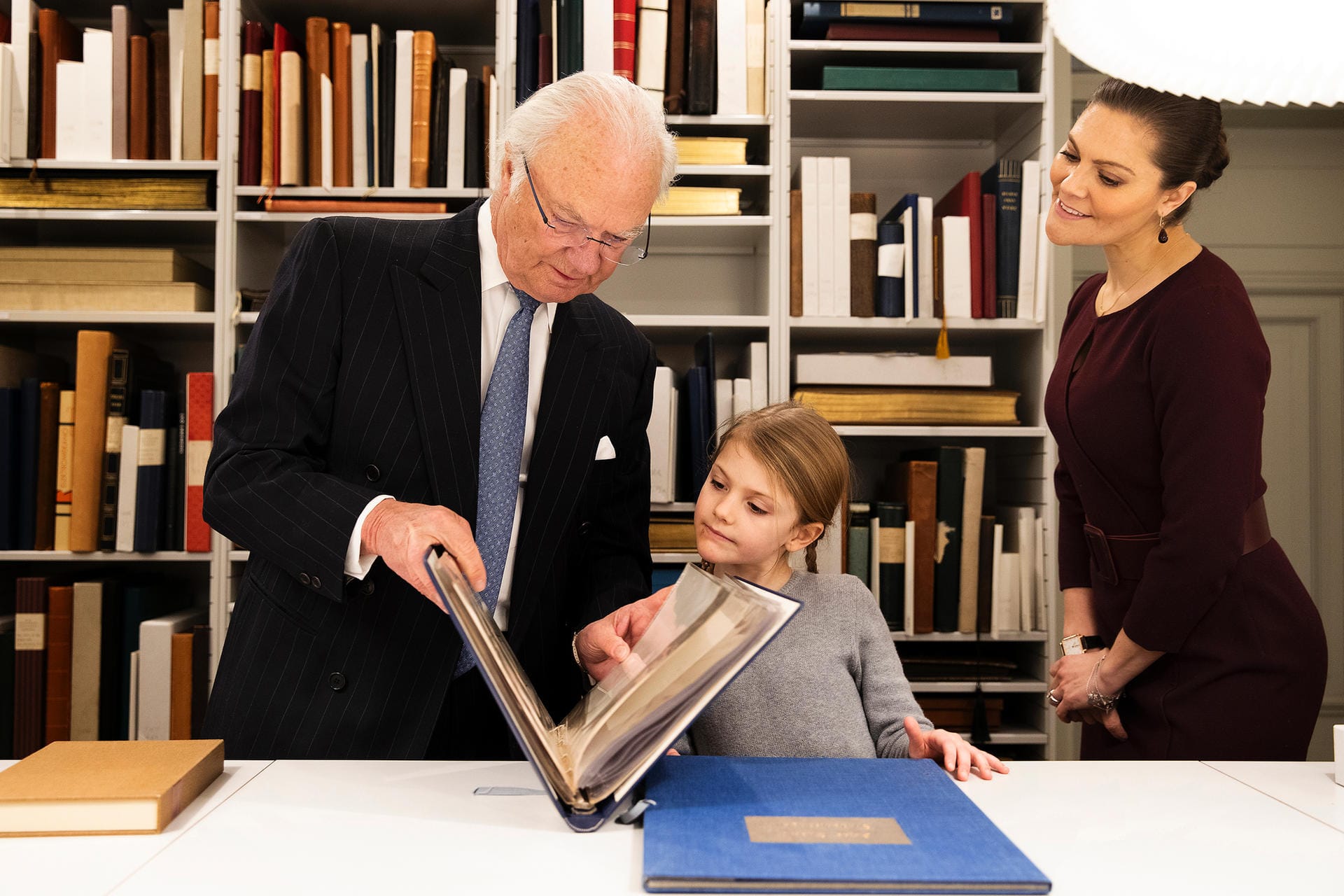 Mit dem Großvater: König Carl Gustaf zeigt seiner Enkelin etwas in einem Ordner. Da schaut auch Victoria ganz interessiert zu.