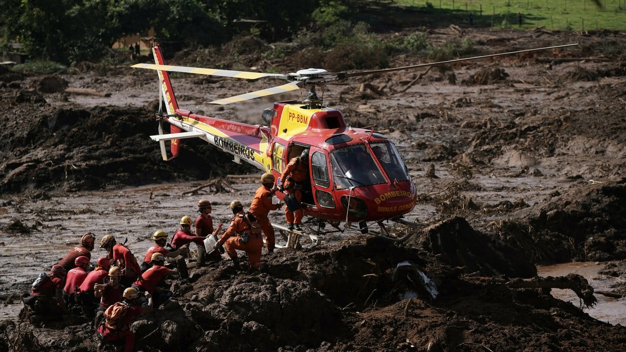 Ein Hubschrauber landet neben Feuerwehrleuten, die nach Opfern im Schlamm suchen. Ein Hubschrauber landet neben Feuerwehrleuten, die nach Opfern im Schlamm suchen.