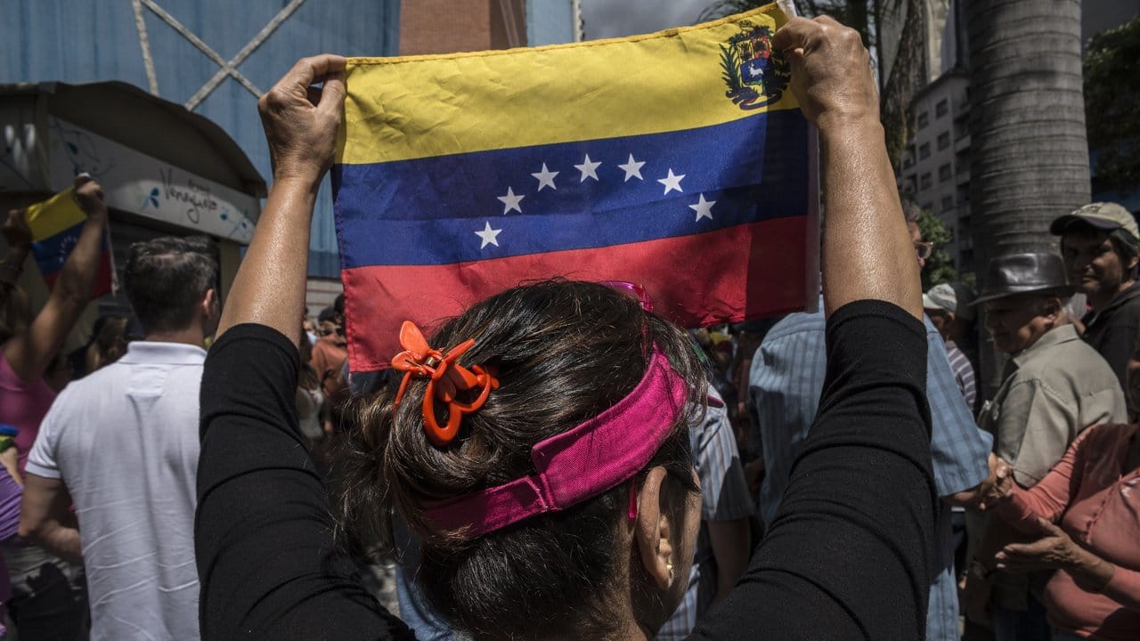 Eine Frau hält beim Protest gegen die Regierung eine venezolanische Flagge hoch.