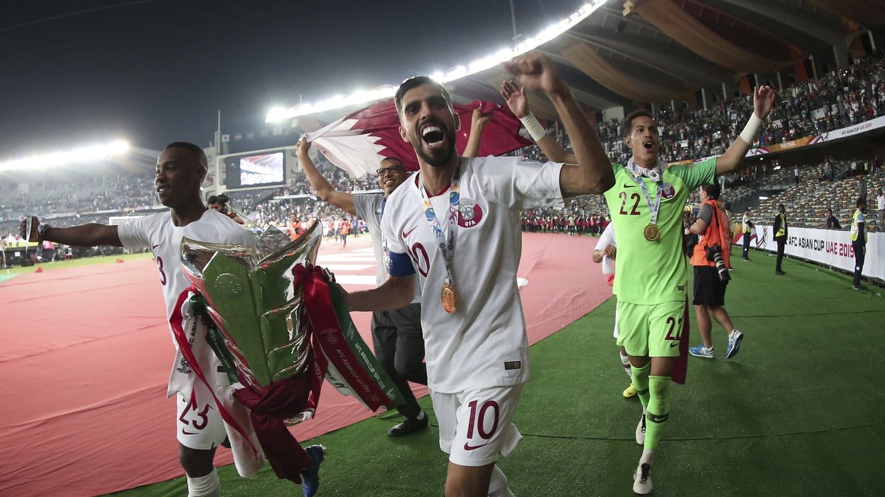 Die Spieler von Katar drehen jubelnd im Zayed Sport City Stadion mit der Trophäe eine Ehrenrunde.