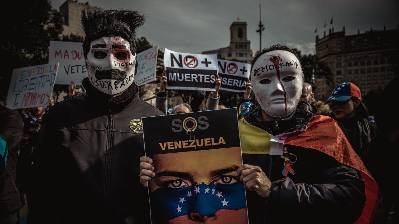 Maduro-kritische Demonstranten tragen bei einem Protestmarsch in Barcelona Masken.