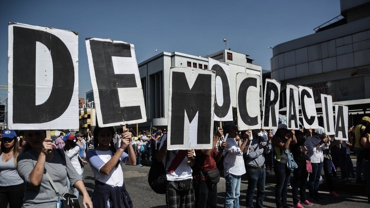 Regierungskritische Demonstranten halten in Caracas Plakate mit dem Schriftzug "Demokratie".