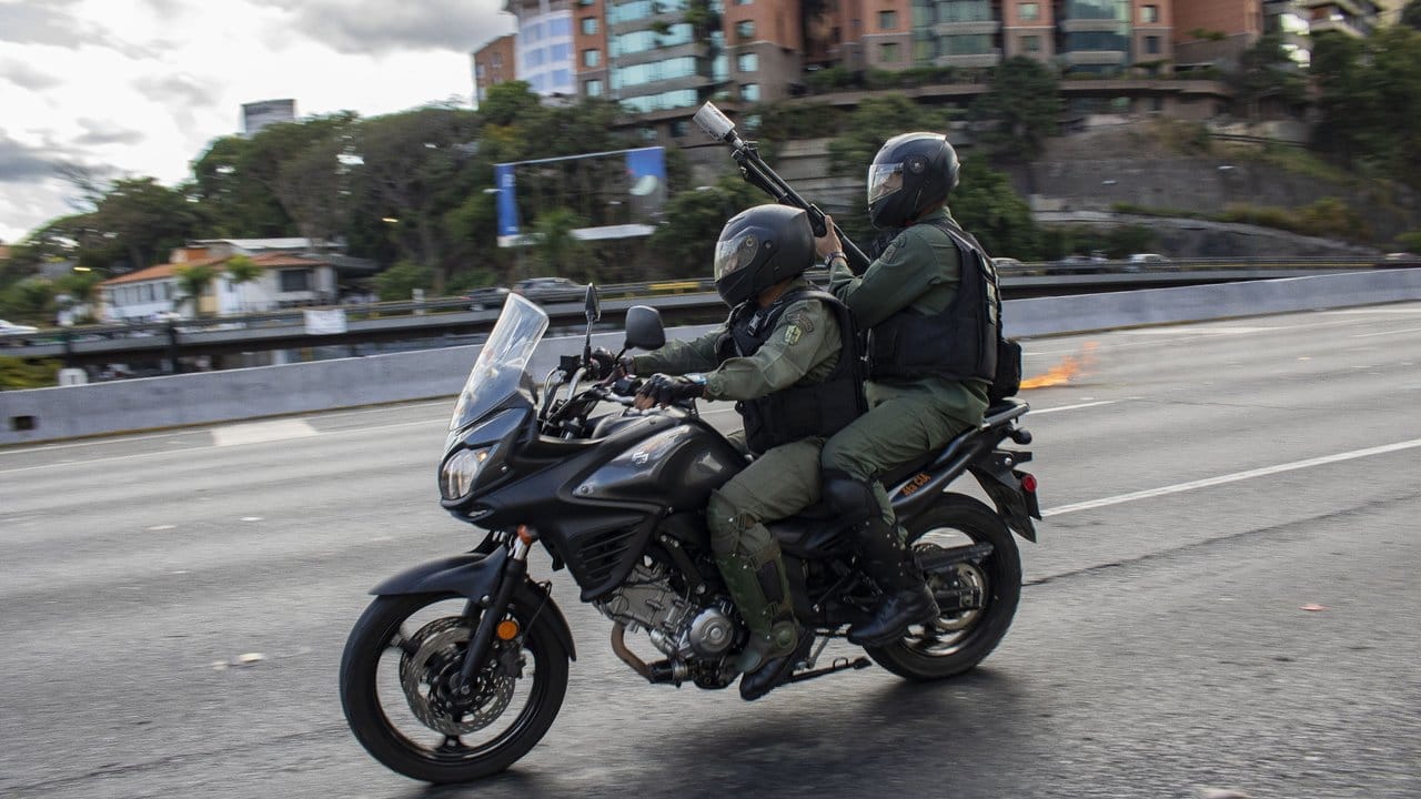 Angehörige der Nationalgarde fahren in Caracas auf einem Motorrad, um Demonstranten zu vertreiben.