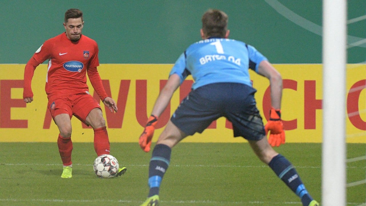 Heidenheims Nikola Dovedan (l) erzielt gegen Lerverkusens Torwart Lukas Hradecky das 1:1.