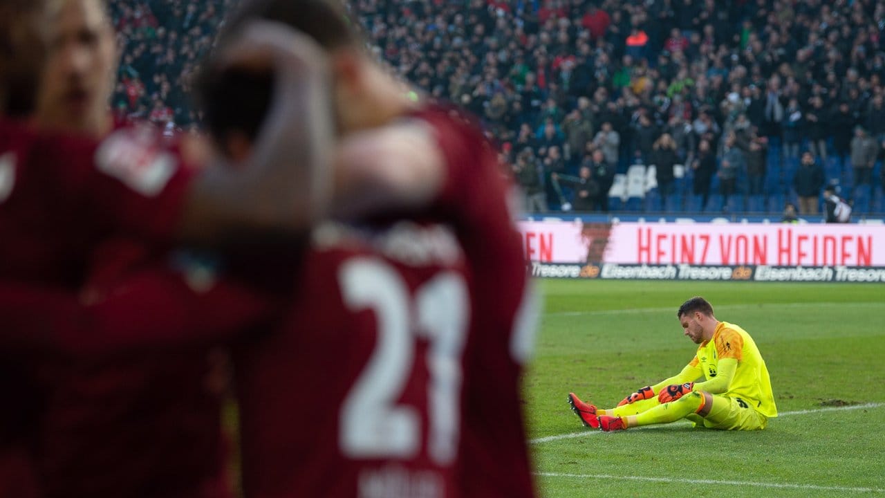 Nürnbergs Torwart Christian Mathenia sitzt am Boden, während Hannovers Spieler nach den 2:0 jubeln.