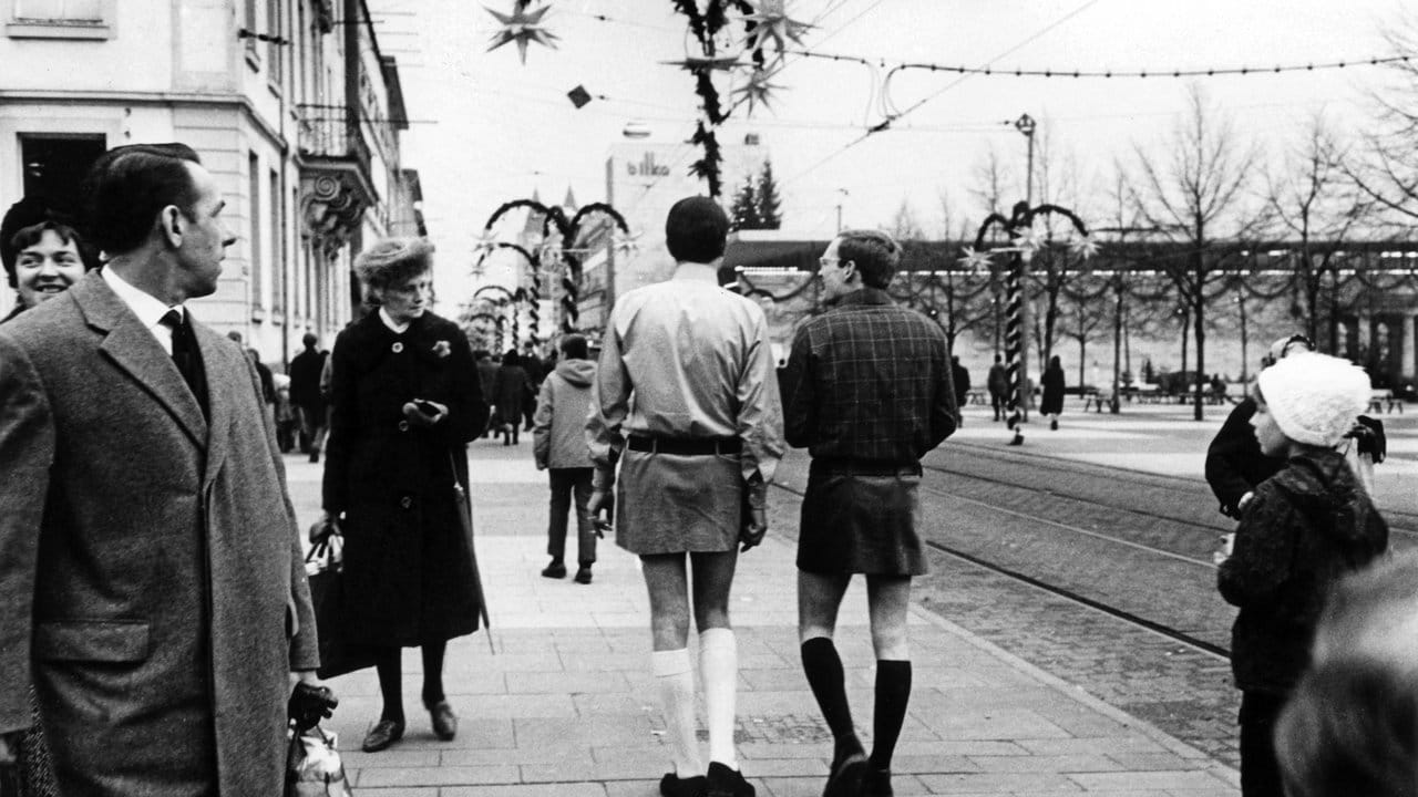 Zwei junge Männer gehen 1966 in Kassel im Mini-Rock durch die Stadt.