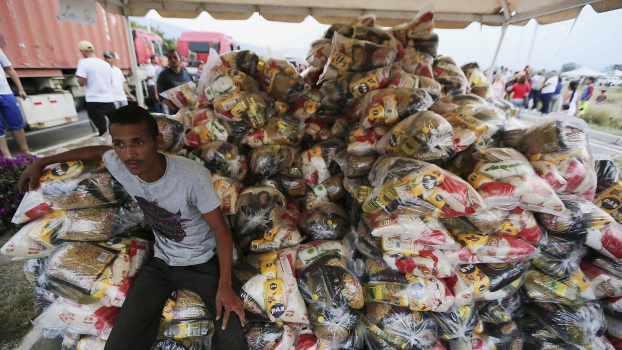 Ein Helfer sitzt neben Tüten mit Lebensmitteln, die von der venezolanischen Regierung im Grenzort Ureña an Bedürftige verteilt werden.