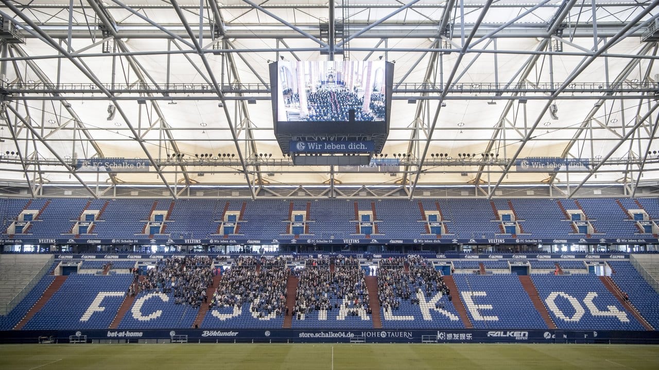 Trauernde Schalke-Fans verfolgen auf dem Videowürfel in der Arena die Gedenkfeier.