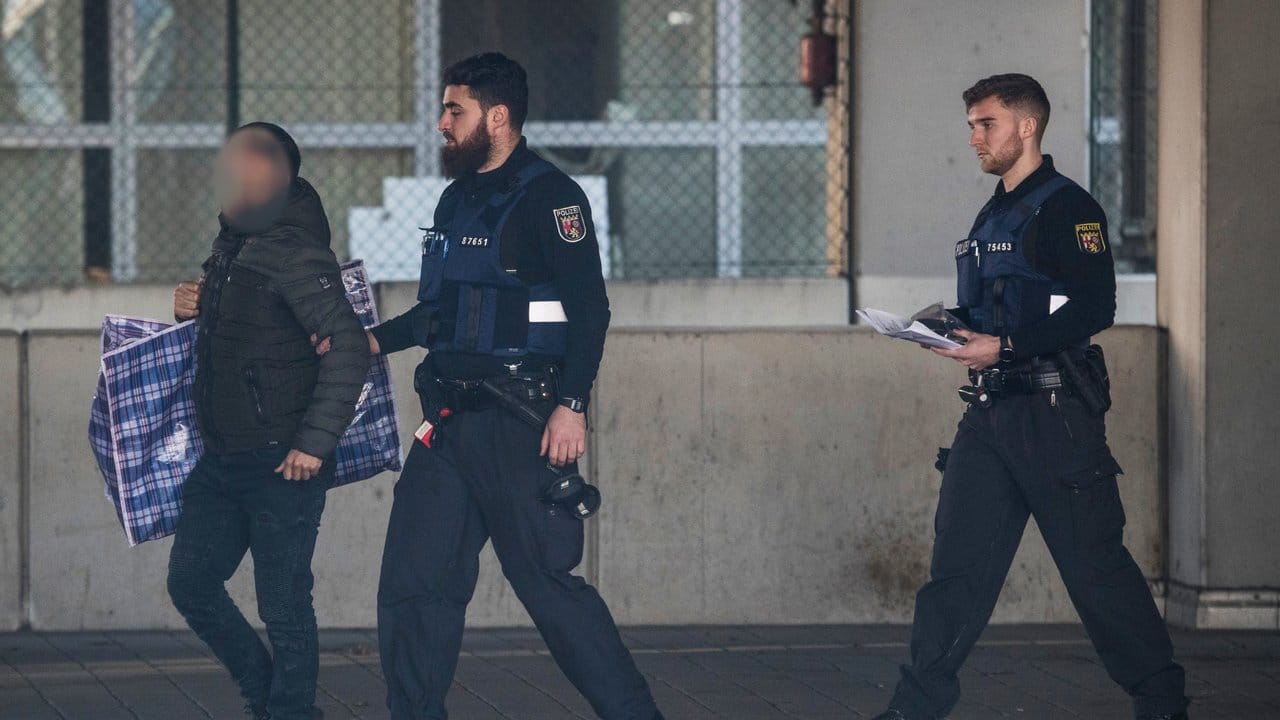 Polizisten begleiten einen Mann (l) in ein Terminal des Flughafens, von wo aus er mit einer gecharterten Maschine am Abend nach Afghanistan abgeschoben werden soll.