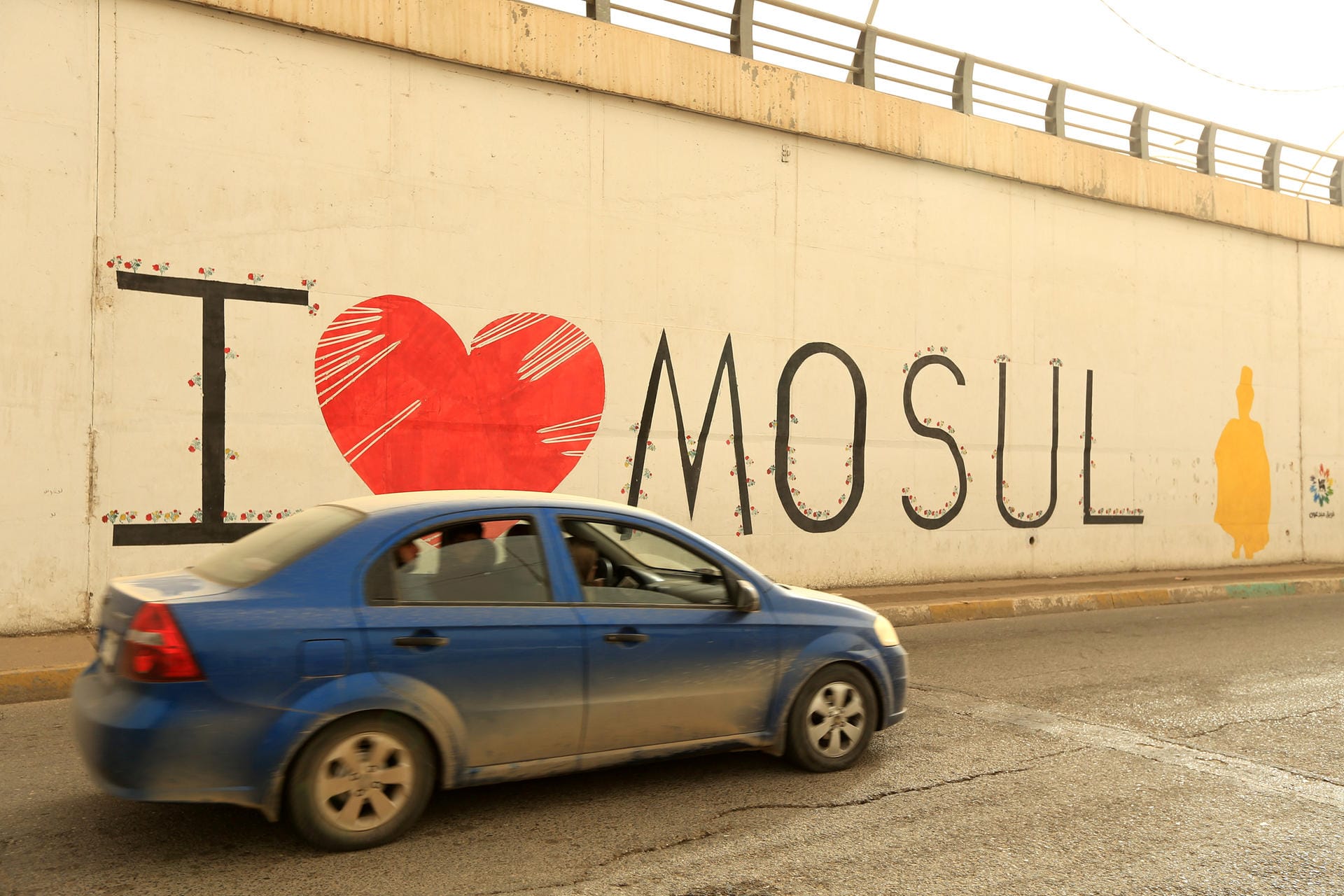 Identifikation mit der Heimatstadt: Ein Auto fährt an einem Graffiti vorbei, auf dem "Ich liebe Mossul" steht.
