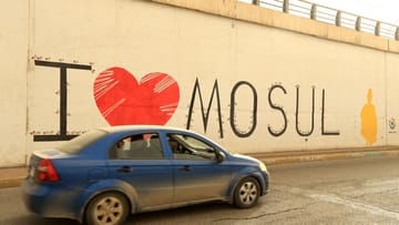 Identifikation mit der Heimatstadt: Ein Auto fährt an einem Graffiti vorbei, auf dem "Ich liebe Mossul" steht.
