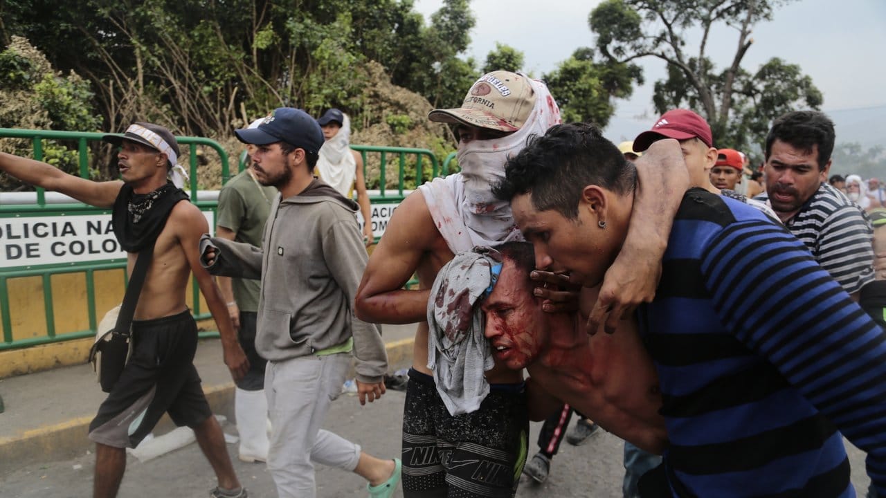 Ein verletzter Demonstrant wird an der Grenze zu Kolumbien in Sicherheit gebracht.