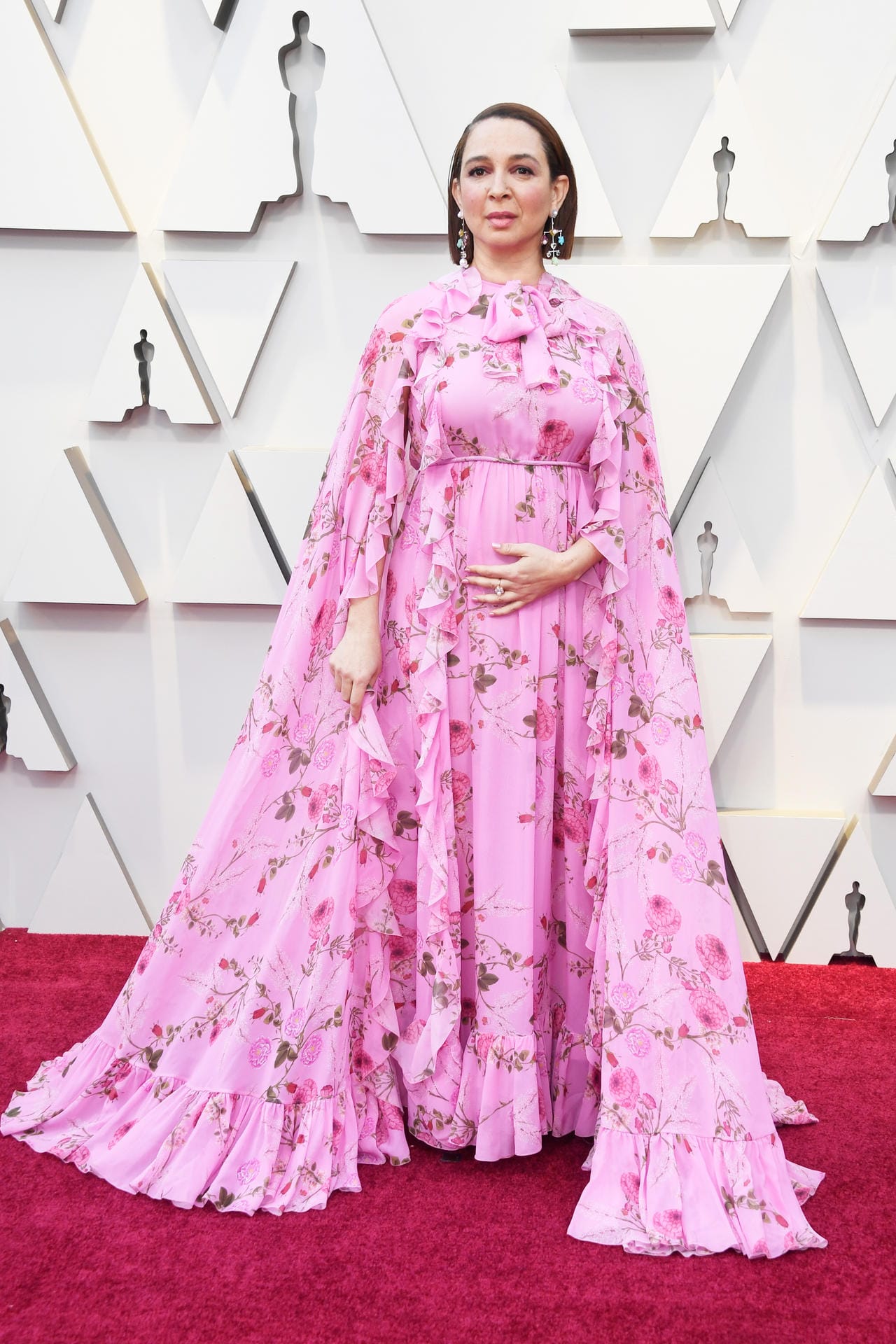 Maya Rudolph: Pink, Blumen, Rüschen und ein Cape – die Schauspielerin trägt ein Kleid mit vielen Stilelementen.
