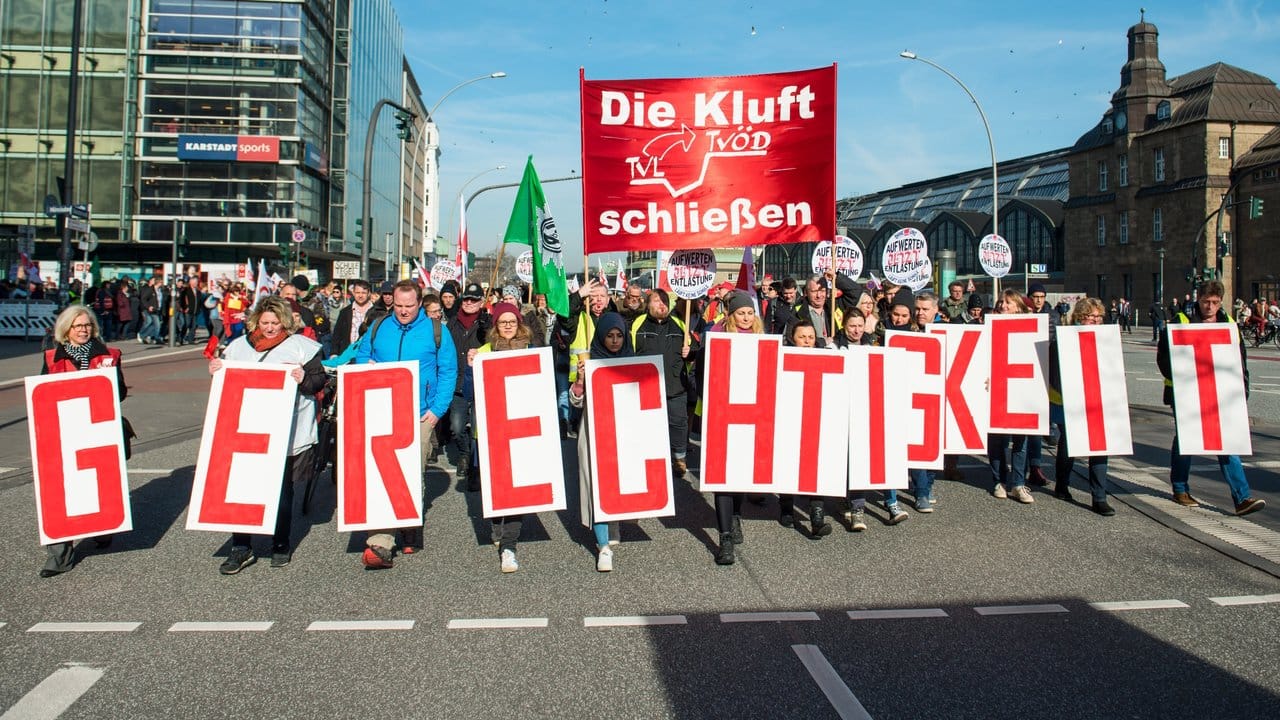 Mitarbeiter des öffentlichen Dienstes in Hamburg ziehen durch die Innenstadt und halten Schilder mit der Aufschrift "Gerechtigkeit".