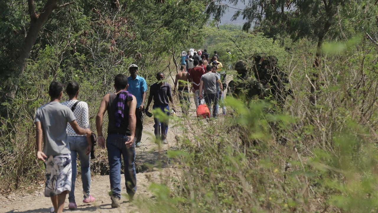 Eine Gruppe Menschen läuft über einen Feldweg von Venezuela nach Kolumbien.