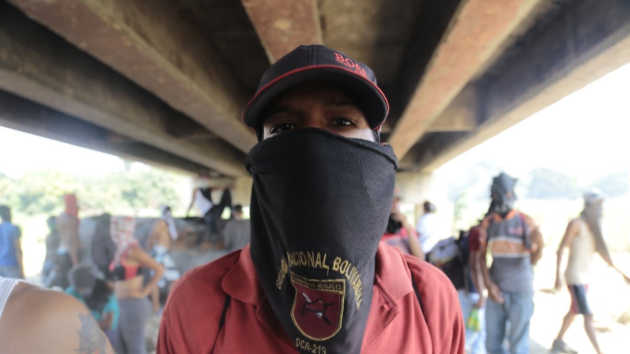 Auch die Regierung hat ihre Anhänger: Ein vermummter Demonstrant, der Maduro unterstützt, steht unter der Grenzbrücke zwischen Kolumbien und Venezuela.