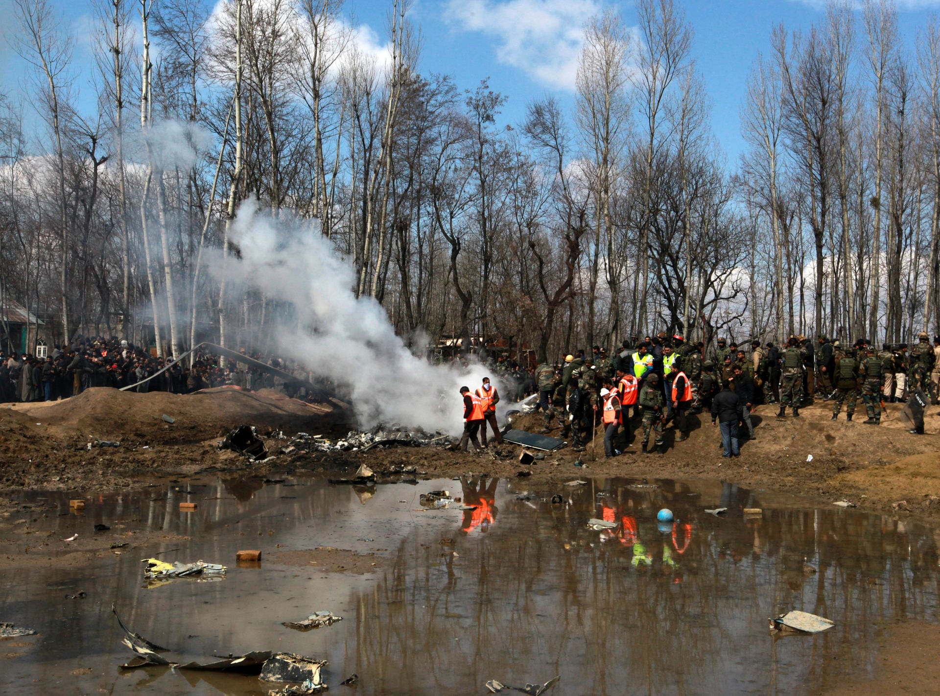 Dorfbewohner stehen vor Trümmern eines Kampfjets