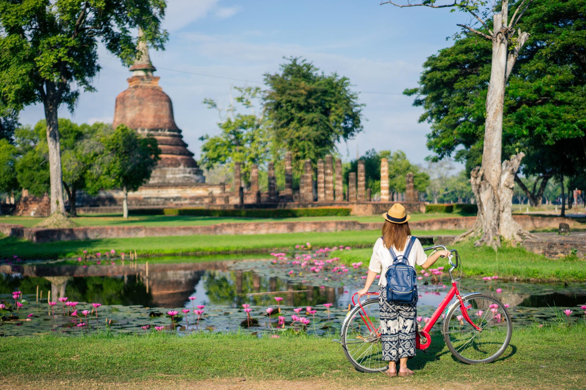 Frau vor dem Tempel Wat Mahathat: In Bangkok können Reisende Partys feiern, aber auch buddhistische Tempel entdecken.