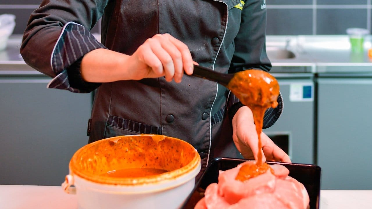 Vor dem Verkauf mariniert die Auszubildende Diana Kari das Fleisch.