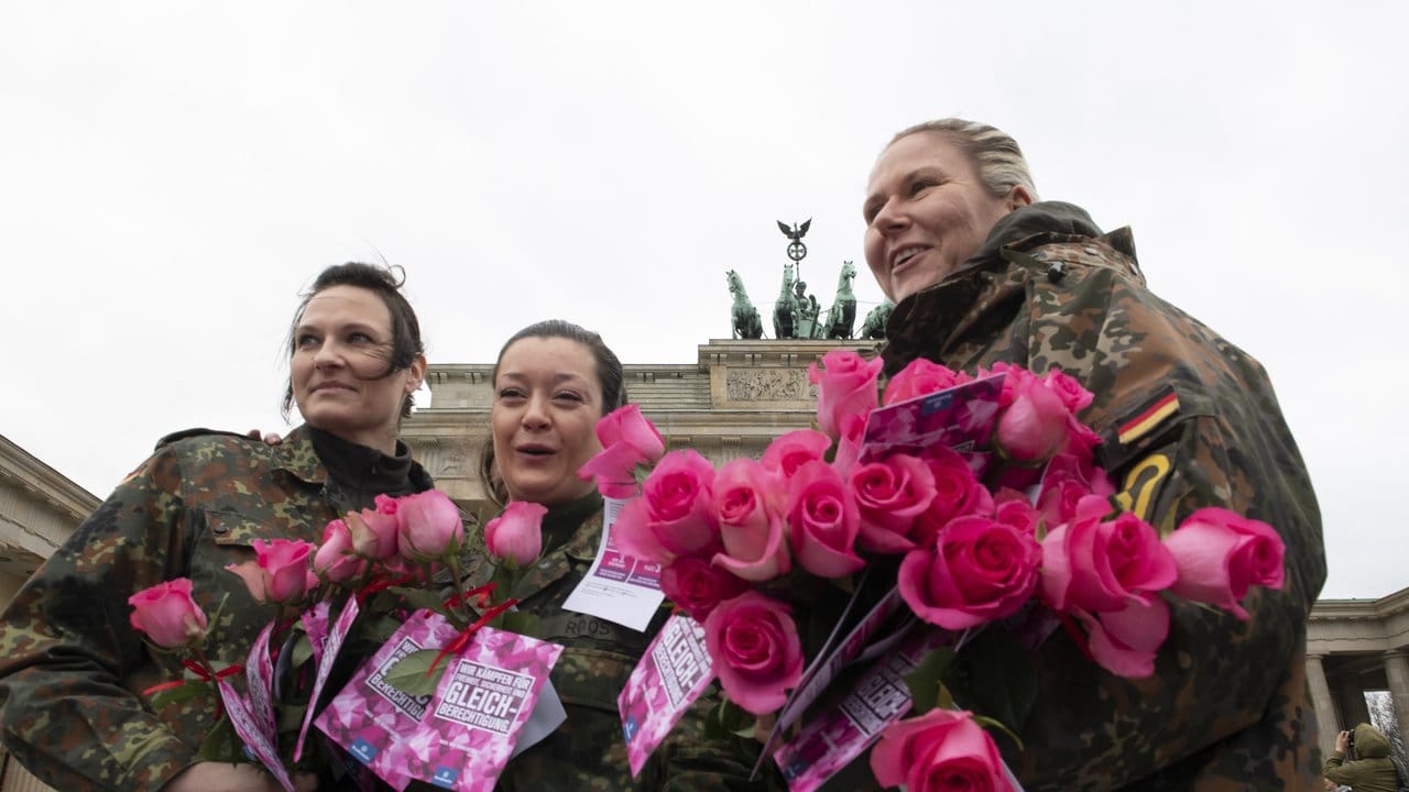 Soldatinnen der Bundeswehr verteilen vor dem Brandenburger Tor Blumen.