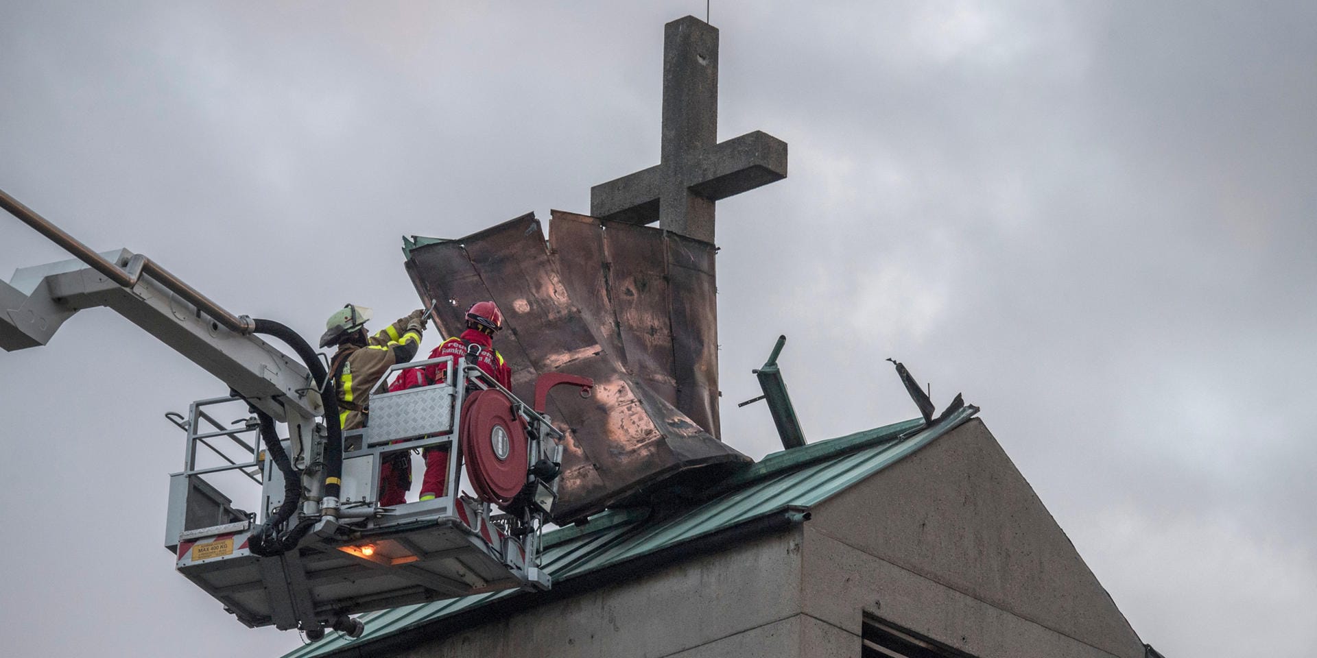 Auch in Hessen wütete "Eberhard": Von einem Hubsteiger aus versuchen Feuerwehrmänner im Frankfurter Stadteil Galles das Blechdach eines Kirchturms zu sichern, das sich durch den Sturm losgerissen hatte.