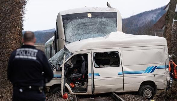 Stark beschädigter Transporter vor einem Zug auf den Bahngleisen: Nach Polizeiangaben hatte der Transporterfahrer den Zug übersehen.