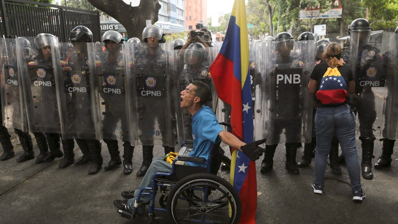 Ungleiche Machtverhältnisse: Ein Demonstrant im Rollstuhl beschimpft Polizisten, die ihn nicht zu einer Demonstration gegen Präsident Maduro durchlassen wollen.