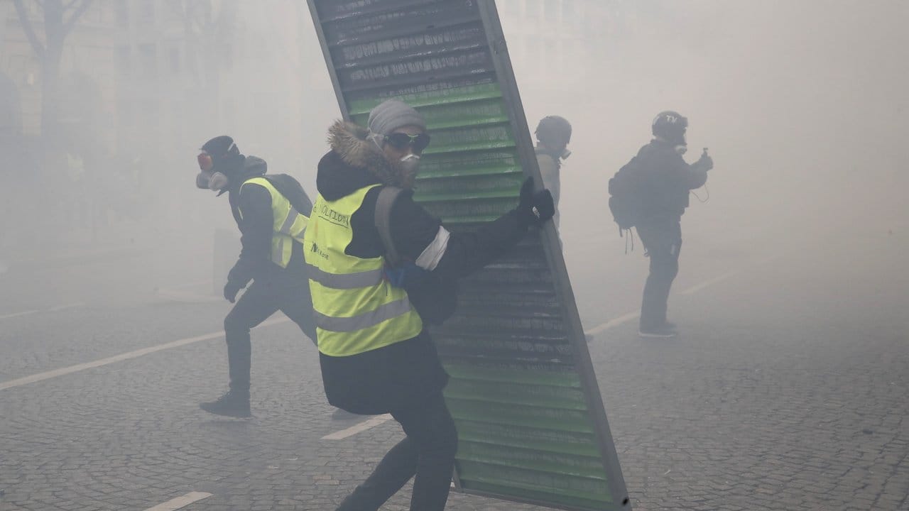Im Tränengasnebel errichten Demonstranten Barrikaden auf den Champs-Elysees.