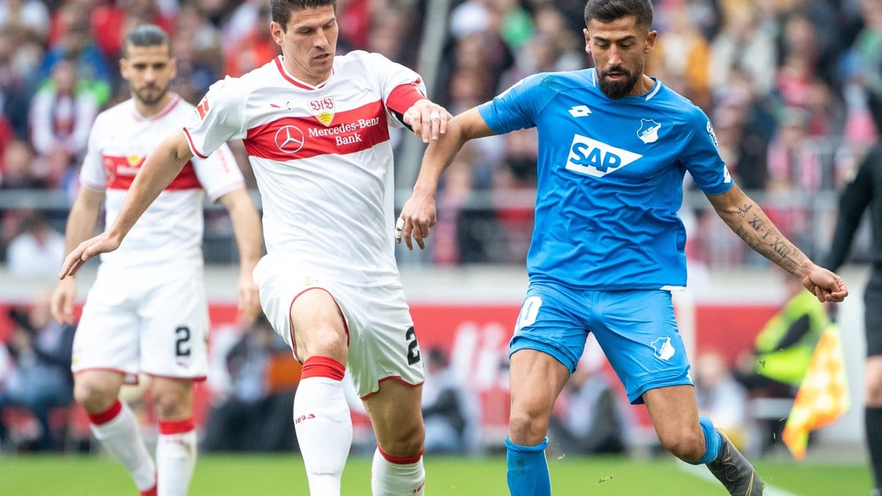 Stuttgarts Mario Gomez (M) im Laufduell mit Hoffenheims Kerem Demirbay.