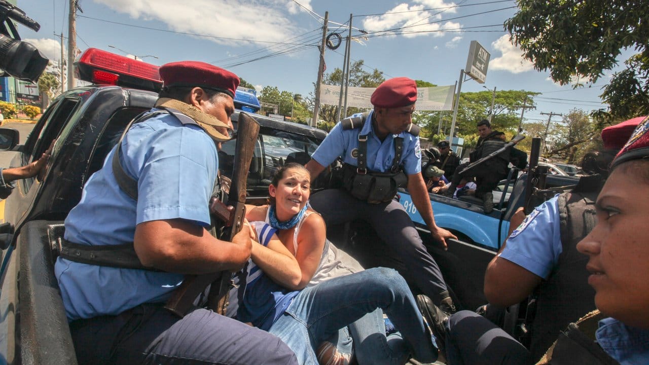 Polizisten sitzen mit festgenommenen Demonstranten auf der Ladefläche eines Fahrzeuges in Managua.