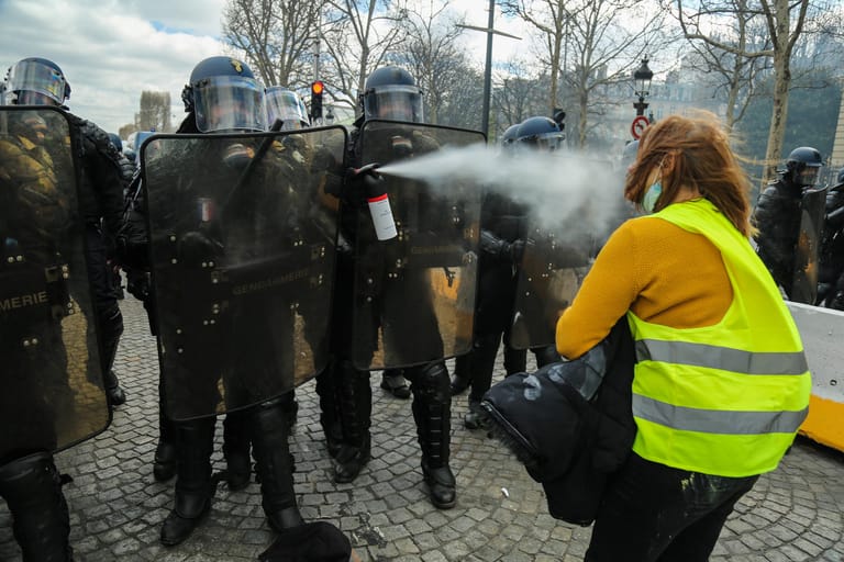 Französische Polizisten verwenden Pfefferspray gegen eine Demonstrantin.