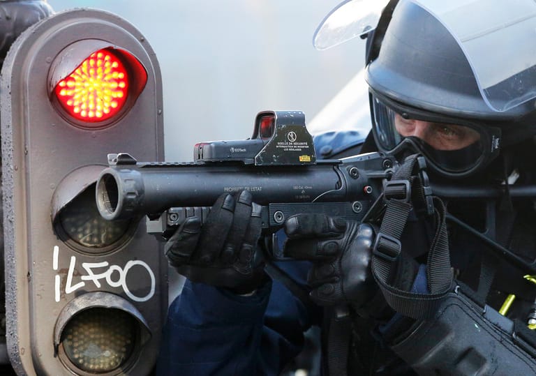 Ein französischer Bereitschaftspolizist zielt auf Protestierende.