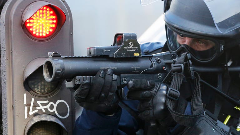 Ein französischer Bereitschaftspolizist zielt auf Protestierende.