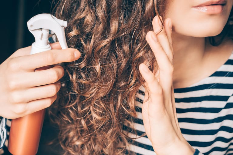 Pflegespray mit lockigen Haaren: Bei gefärbten Haaren ist die regelmäßige Pflege wichtig.