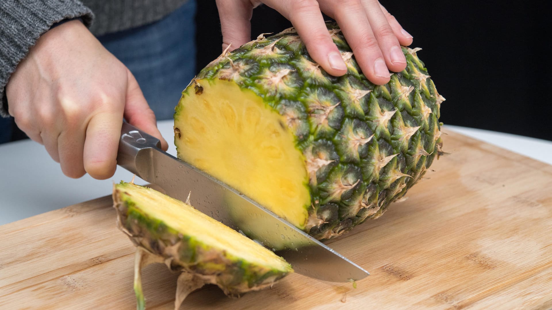 Ananas richtig aufschneiden: Schritt 2 – Das untere Ende der Ananas ebenfalls abschneiden.