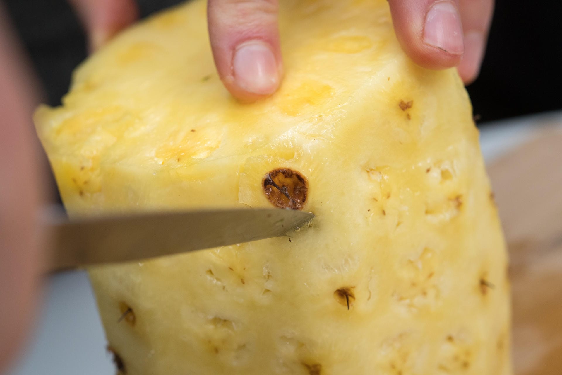 Ananas richtig aufschneiden: Schritt 5 – Mit einem kleinen Küchenmesser die Augen rundherum herausschneiden.