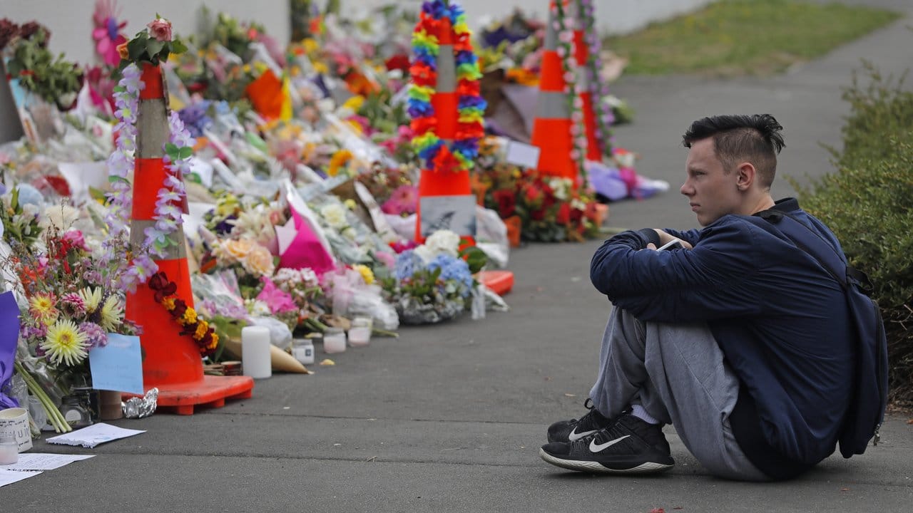 Ein Schüler sitzt vor Blumen, die in Christchurch in Gedenken an die Opfer des Anschlages niedergelegt wurden.