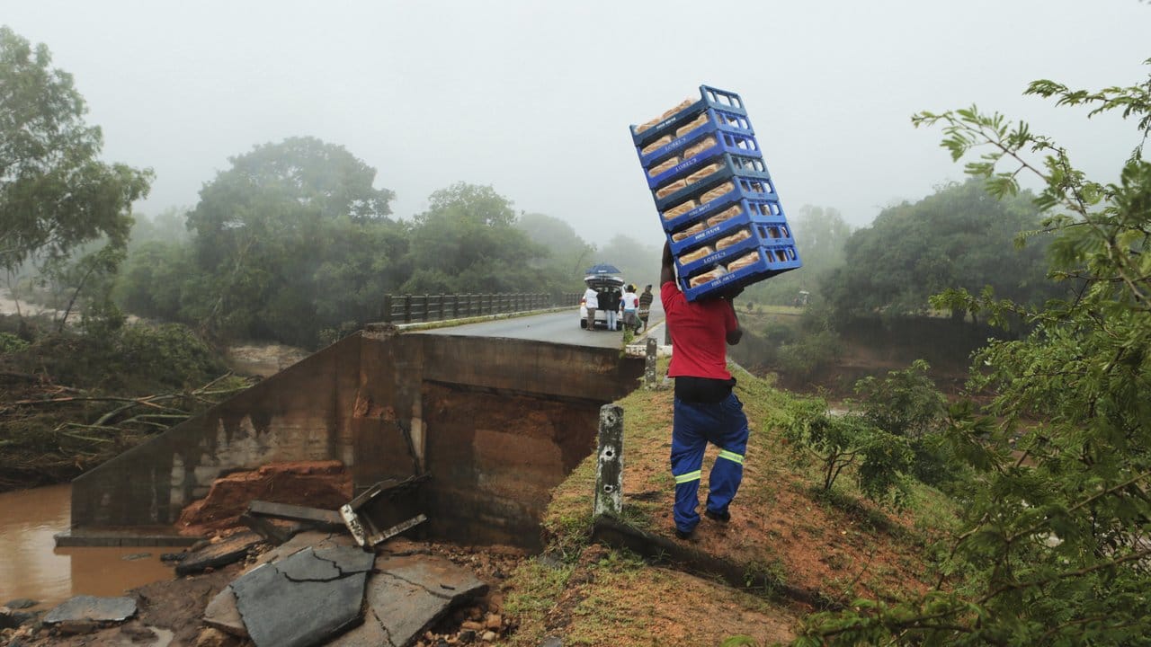 Ein Mann trägt Brote über eine eingestürzte Brücke.