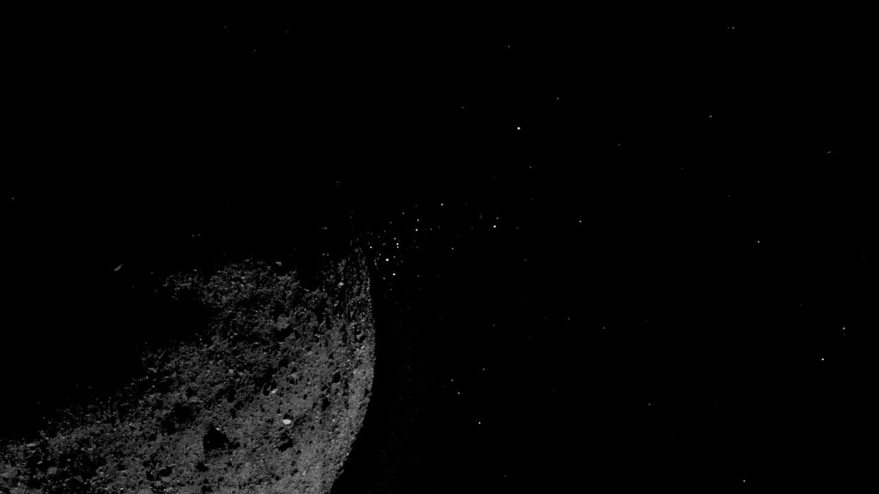 Die Aufnahme der Sonde Osiris Rex zeigt das Teile die sich von der Oberfläche des Asteroiden Bennu lösen.