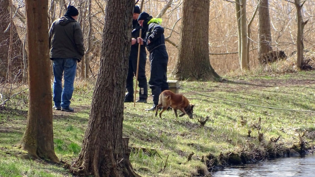 Polizeibeamte mit einem Spürhund suchen am Ufer des Storkower Kanals nahe dem Wolziger See nach Rebecca.