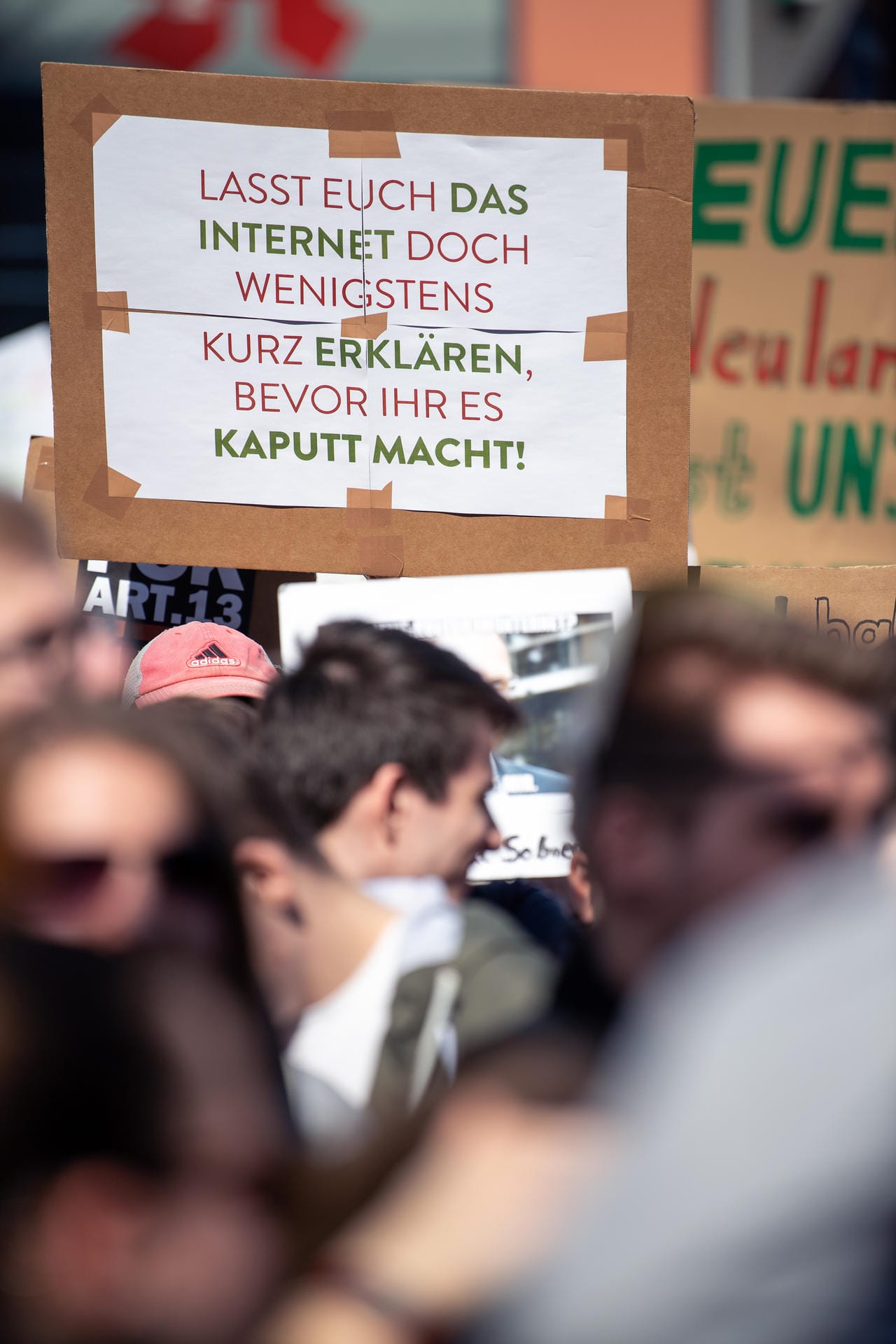 In Stuttgart hält eine Teilnehmerin hält ein Schild hoch, auf dem steht: "Lasst Euch das Internet doch wenigstens kurz erklären, bevor ihr es kaputt macht!".