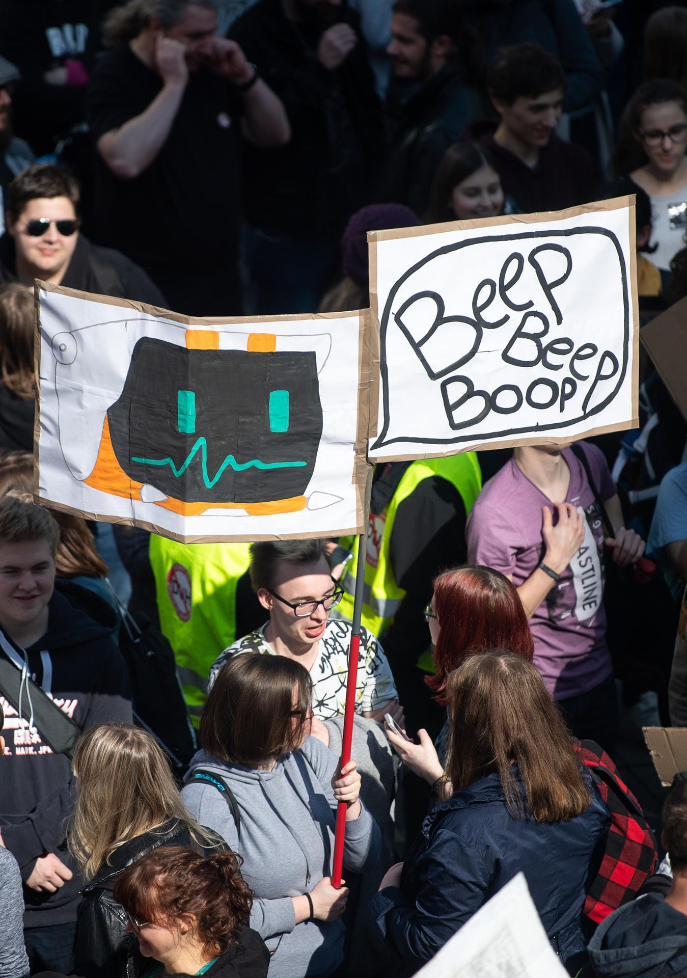 Eine Teilnehmerin in Stuttgart hält ein Schild hoch, auf dem in Anspielung auf Bots "Beep Beep Boop" steht.