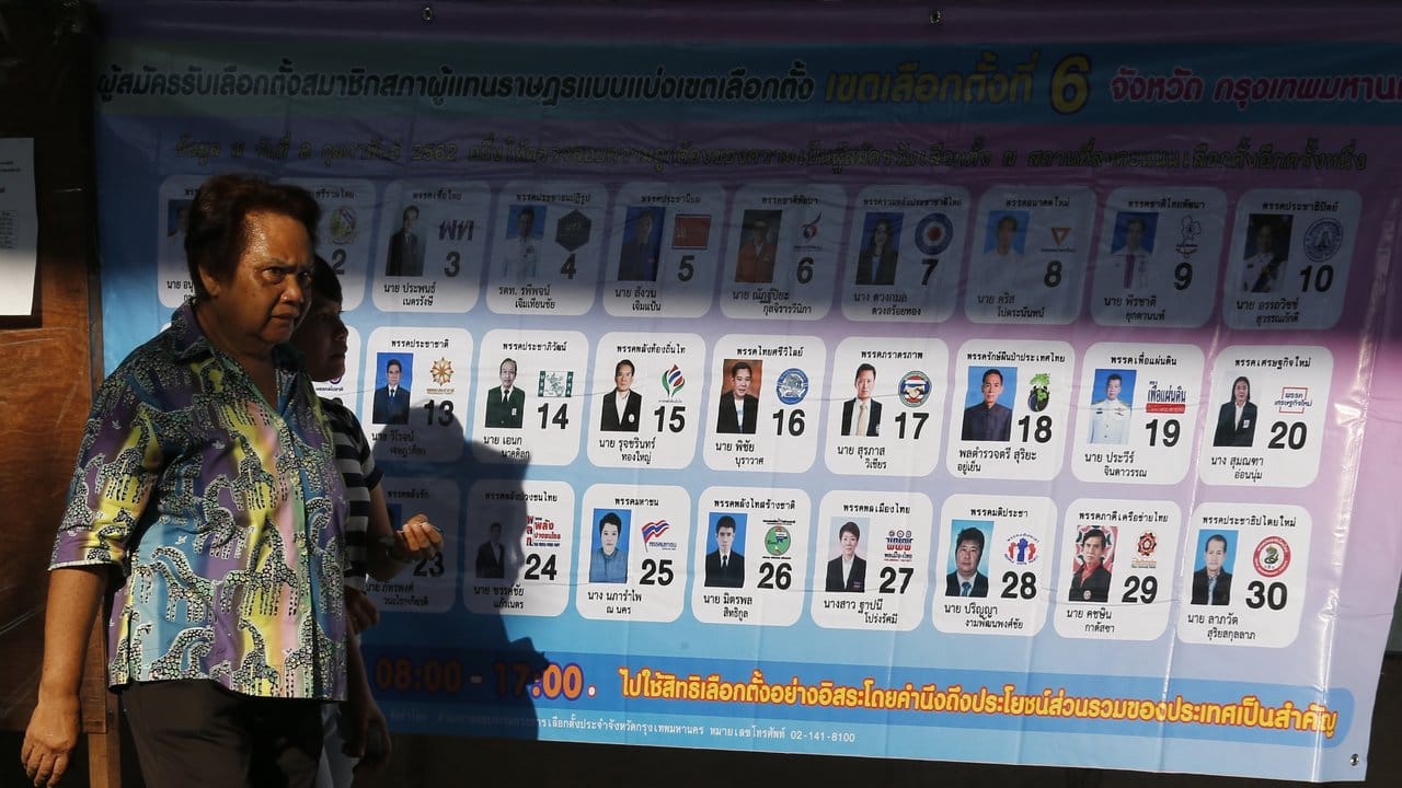 Eine Frau geht an einem Plakat mit den Kandidaten der Parteien vorbei.