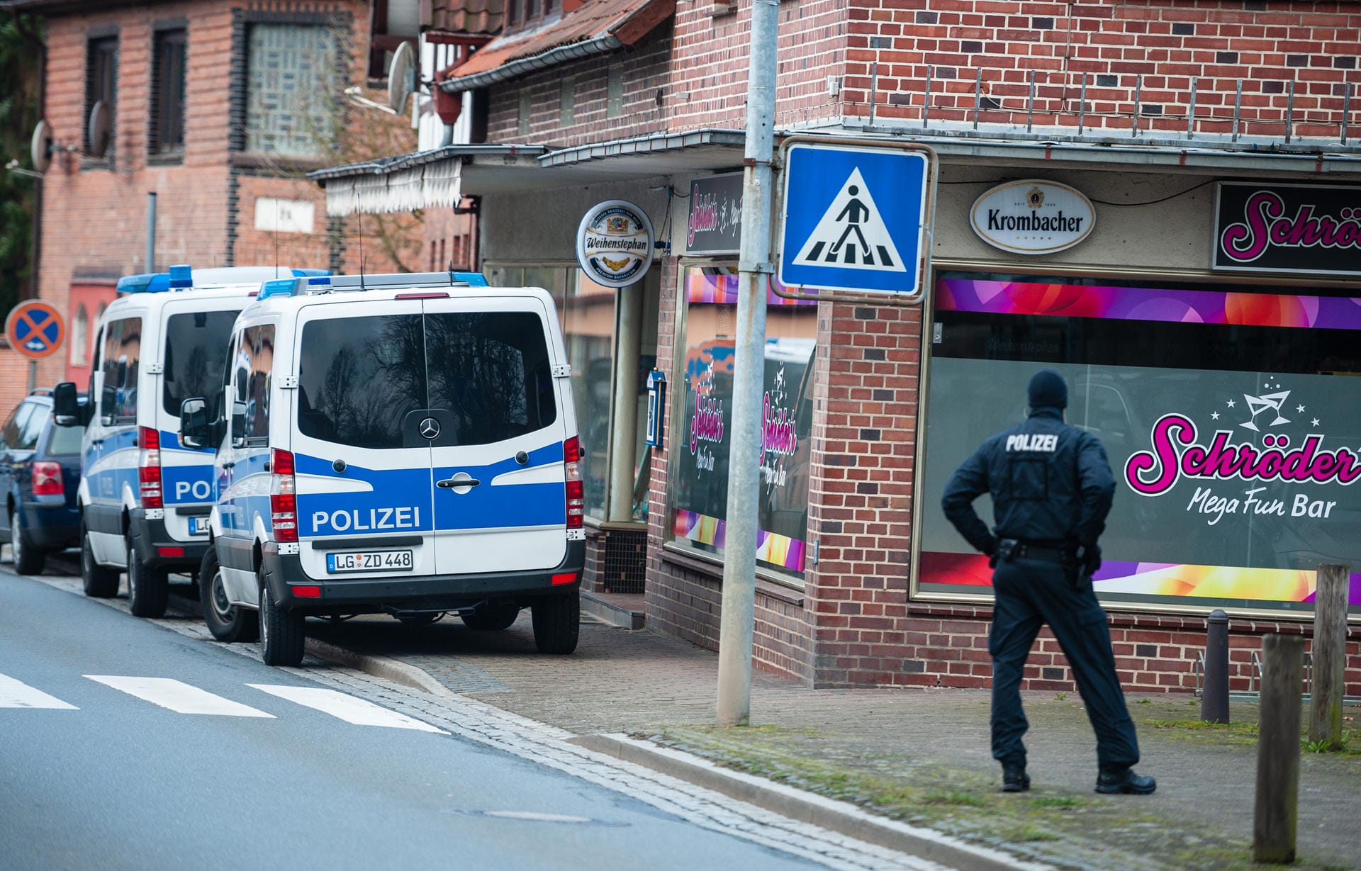 Polizeiwagen und ein Ermittler stehen vor einer Bar: Mehr als 200 Ermittler durchsuchten seit Mittwochmorgen 13 Gebäude in Norddeutschland.